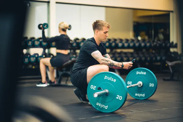 Member with Pulse Fitness free weights and barbell